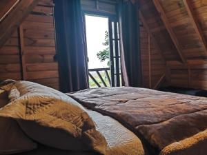 a bed in a room with a large window at Chalé na Vila Do Sossego in Alfredo Wagner