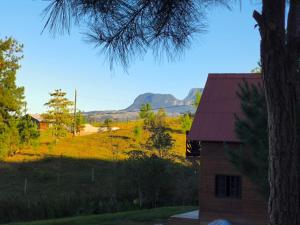 a barn with a view of a field and mountains at Chalé na Vila Do Sossego in Alfredo Wagner