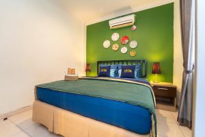 a bedroom with a blue bed with a green wall at Roemah Noni Baciro By ARBA in Demangan