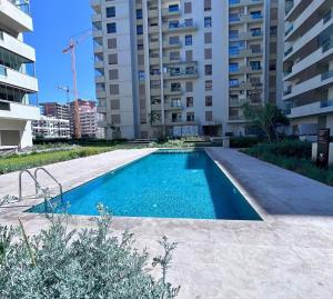 a swimming pool in front of a tall building at Charmant studio, piscine proche mer in Aïn Harrouda
