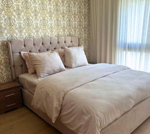 a bed with white sheets and pillows next to a window at Charmant studio, piscine proche mer in Aïn Harrouda +9 photos