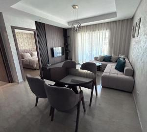 a living room with a couch and a table and chairs at Charmant studio, piscine proche mer in Aïn Harrouda