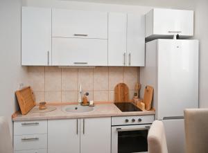 a kitchen with white cabinets and a sink at Apratman Shine Kula in Kula