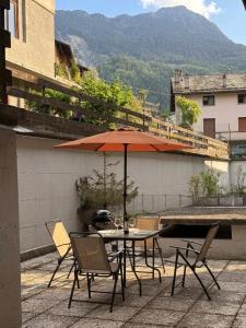 a table and chairs with an umbrella on a patio at Dolce Vetta Valmalenco in Chiesa in Valmalenco