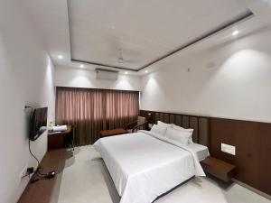 a bedroom with a large white bed and a television at MRP Residency in Chitradurga