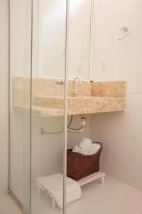 uma casa de banho com um chuveiro, um lavatório e uma cesta. em Pousada Macamirim em Macaíba