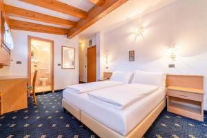 a bedroom with a large white bed and a bathroom at Pineta Pastry Hotel in Rocca Pietore