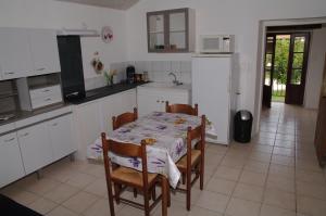 a kitchen with a table and chairs and a kitchen with white cabinets at Gite Le Banchet in Truinas