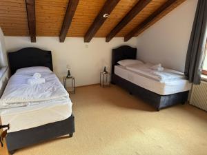two twin beds in a room with wooden ceilings at Cozy Attic in Berkach