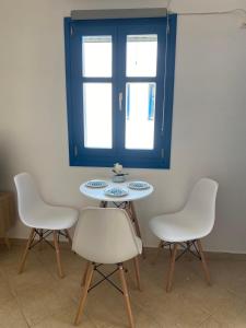 a table with three chairs and a blue window at Casa Ariadne in Náxos