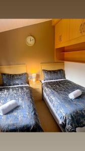 two beds in a bedroom with a clock on the wall at ocean view 15 in West Down