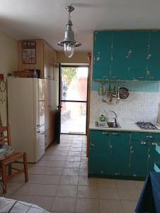 a kitchen with green cabinets and a white refrigerator at gialos house in Livadia