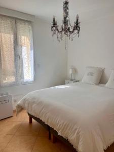 a bedroom with a large white bed with a chandelier at Coeur Cevennes in La GrandʼCombe