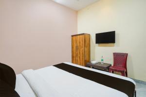 a bedroom with a bed and a table and a television at HOTEL O STAR INN in Raipur