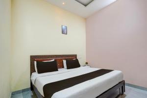 a bedroom with a large white bed with black pillows at HOTEL O STAR INN in Raipur