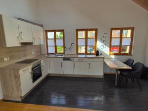 a kitchen with white cabinets and a table and windows at LIV Retreat in Dietenhofen +3 photos