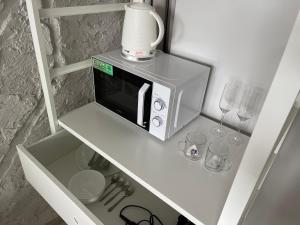 a microwave sitting on top of a shelf with glasses at Central place with lake view in Šiauliai