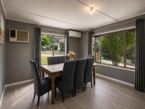a dining room with a wooden table and chairs at The Cove - Lake Eildon in Piries +5 photos