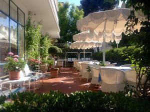 a patio with white tables and chairs and an umbrella at Hotel Solitude in Riccione