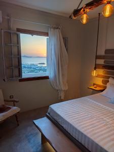 a bedroom with a bed and a window with a view at Zephyrus Sunset House. Amazing View and Privacy! in Agkidia