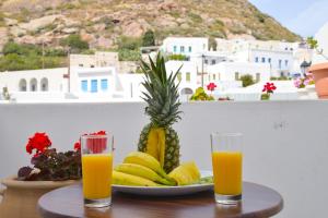 a plate of fruit and two glasses of orange juice at Kastro View Apartment in Plaka Milou
