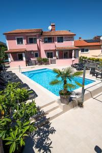 a swimming pool in front of a house with chairs at Apartments Anita in Pula