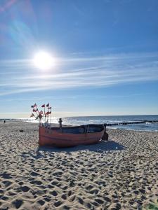 a boat sitting on a sandy beach with the ocean at Villetta Rewal in Rewal