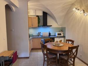 a kitchen with a table and a dining room at Le Secret d'Adèle in Chateauroux-les-Alpes