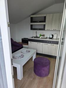 eine kleine Küche mit einem weißen Tisch und einem lila Hocker in der Unterkunft Lily 2 in Ljubuški