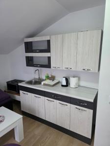 eine Küche mit weißen Schränken und einer Spüle in der Unterkunft Lily 2 in Ljubuški