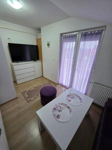 ein Wohnzimmer mit einem weißen Tisch und einem Fernseher in der Unterkunft Lily 2 in Ljubuški