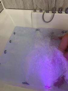 a bathtub filled with purple water with a person in it at Studio with jacuzzi near Atlantic ocean in Myrtle Beach