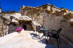 a patio with chairs and a table in a stone building at Tulip Cave Suites in Göreme