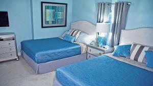 a blue bedroom with two beds and a night stand at Luxury Vacation Escape Free Beach Service Come Relax Book Now! in Panama City Beach
