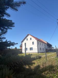 a white house with a fence and a tree at Szlachcianka in Gorzuchów