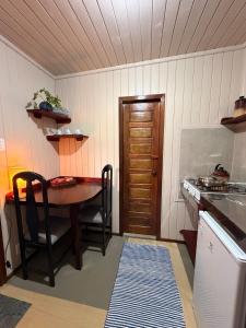 a kitchen with a wooden table and a table and chairs at Pousada Nó de Pinho - Kitnet Microcasa in São Joaquim +16 photos