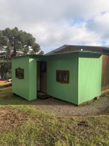 a green shed with a door in a yard at Pousada Nó de Pinho - Kitnet Microcasa in São Joaquim