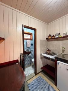 a kitchen with a table and a sink and a toilet at Pousada Nó de Pinho - Kitnet Microcasa in São Joaquim