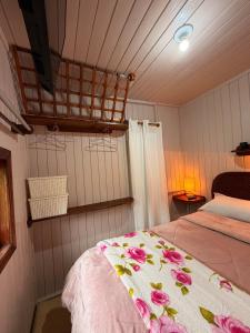 a bedroom with a bed with pink flowers on it at Pousada Nó de Pinho - Kitnet Microcasa in São Joaquim