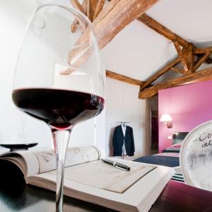 a glass of wine sitting on a table with a book at La Villa des Forges in Legé