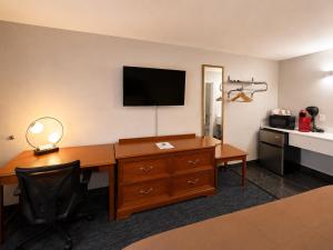 a hotel room with a desk and a television on the wall at Ozark Inn & Suites in Ozark