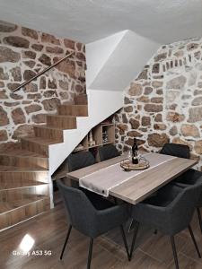 a table and chairs in a room with a stone wall at Kuća Get in Betina