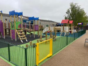 a park with a playground with a fence at The James Lodge in Little Clacton