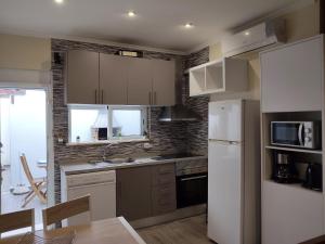 a kitchen with white cabinets and a white refrigerator at Casa Verão Azul in Monte Gordo +23 photos