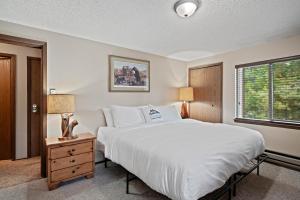 a bedroom with a large white bed and a window at Trapper 8: Cozy 4-Bedroom Condo, 1 Minute to Yellowstone, perfect for 8 guests. in Levokumskoye