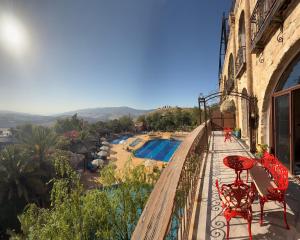 ein Balkon mit Tischen und Stühlen und ein Swimmingpool in der Unterkunft Tal Rumman Boutique Hotel in Gerasa