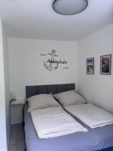 a bed with two white sheets and a sign on the wall at Strandkorb 115 in Rostock +2 photos