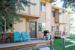 a house with two chairs and a grill on a porch at Trapper 8: Cozy 4-Bedroom Condo, 1 Minute to Yellowstone, perfect for 8 guests. in Levokumskoye