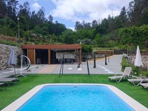 a pool in a yard with chairs and umbrellas at Quinta Cunha in São Pedro do Sul