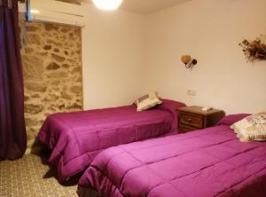 two beds in a room with purple sheets at Casa Rural Roquemar in Guijo de Granadilla